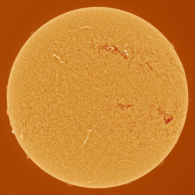 The sun, seen as a large white sphere with small dark spots.