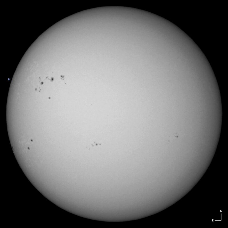 The sun, seen as a large white sphere with small dark spots.