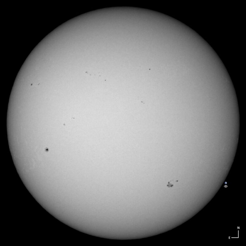 The sun, seen as a large white sphere with small dark spots.