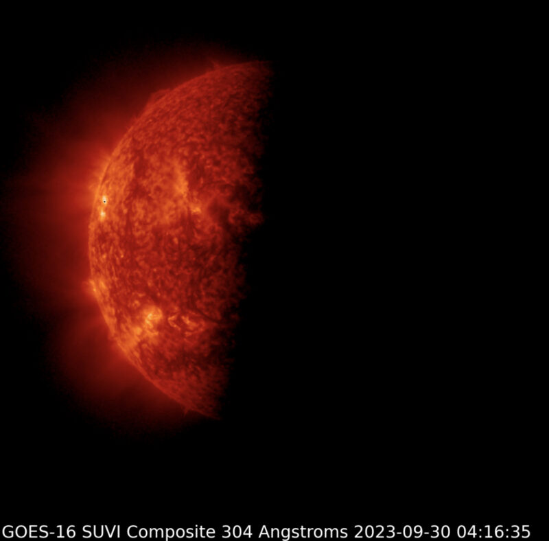 Half red sun with explosions at edge and cloud-like corona.