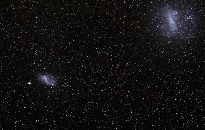 Whitish-blue fuzzy oval in upper right and smaller oval of light at lower left in starfield.