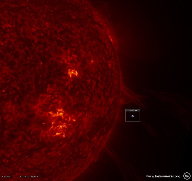 right half of a red sphere with a small image of Earth for scale