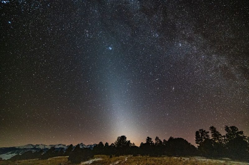 Zodiacal light: Cone of light extending from horizon to cluster of stars in night sky.