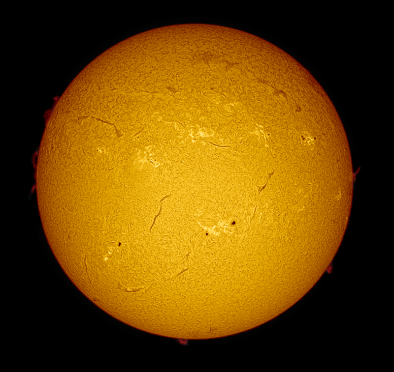 The sun, seen as a large yellow sphere with a mottled surface and dark spots.